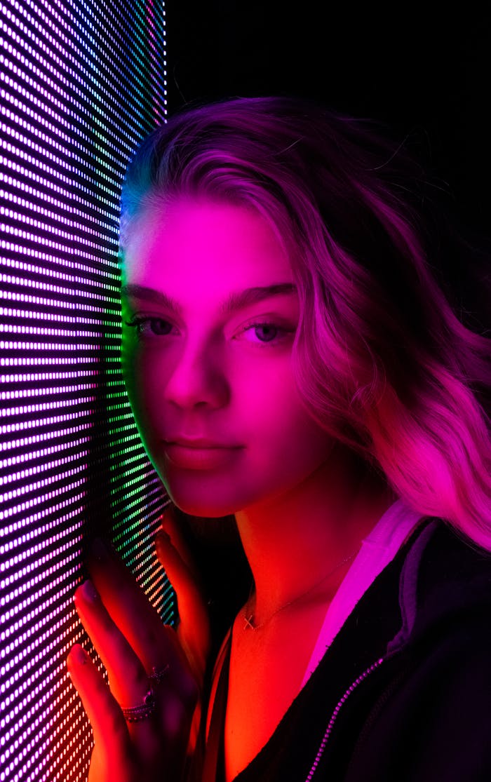 A young woman illuminated by neon lights in a moody and vibrant portrait.